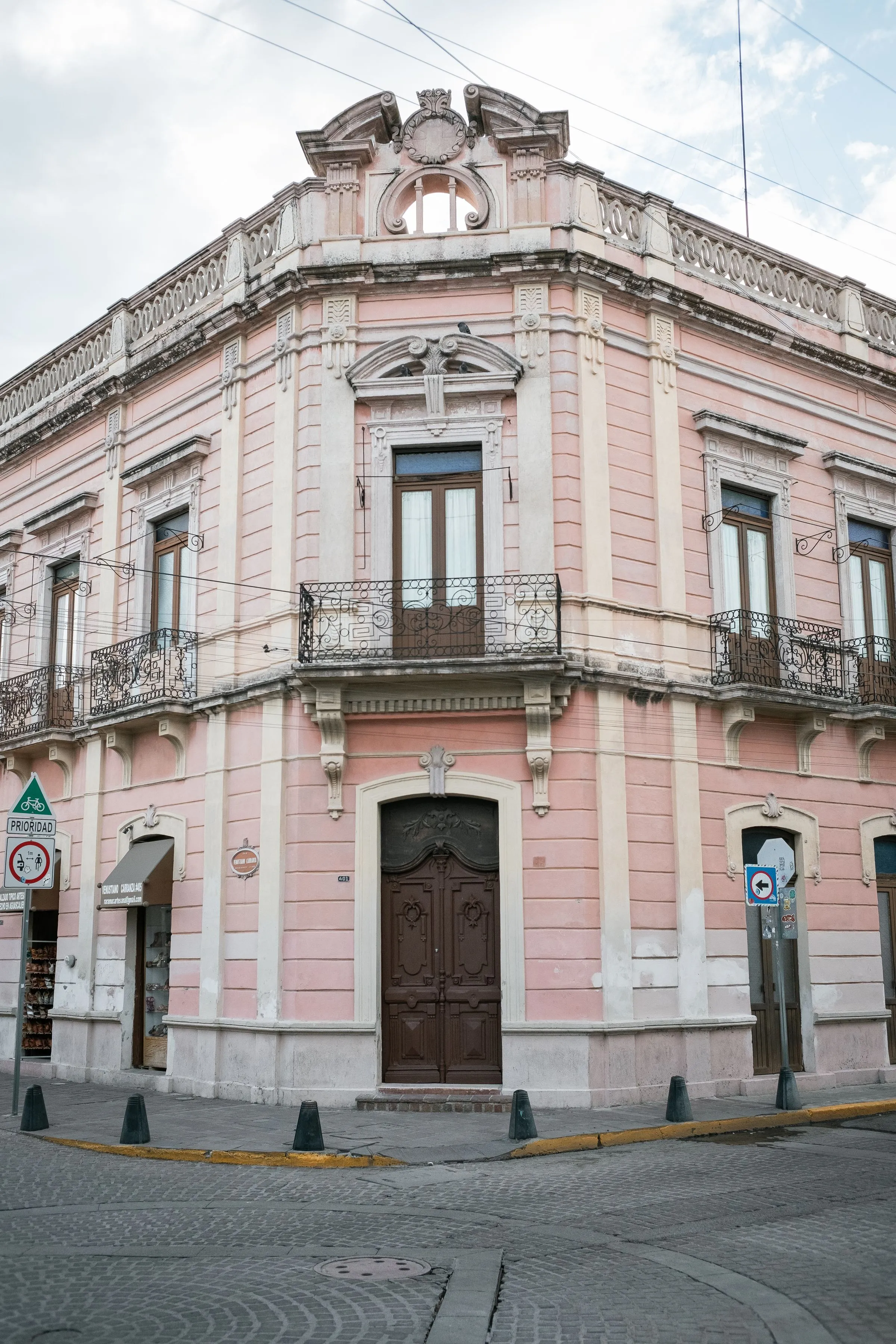Casona colonial rosa con balcones de herrería y portón de madera tallada.