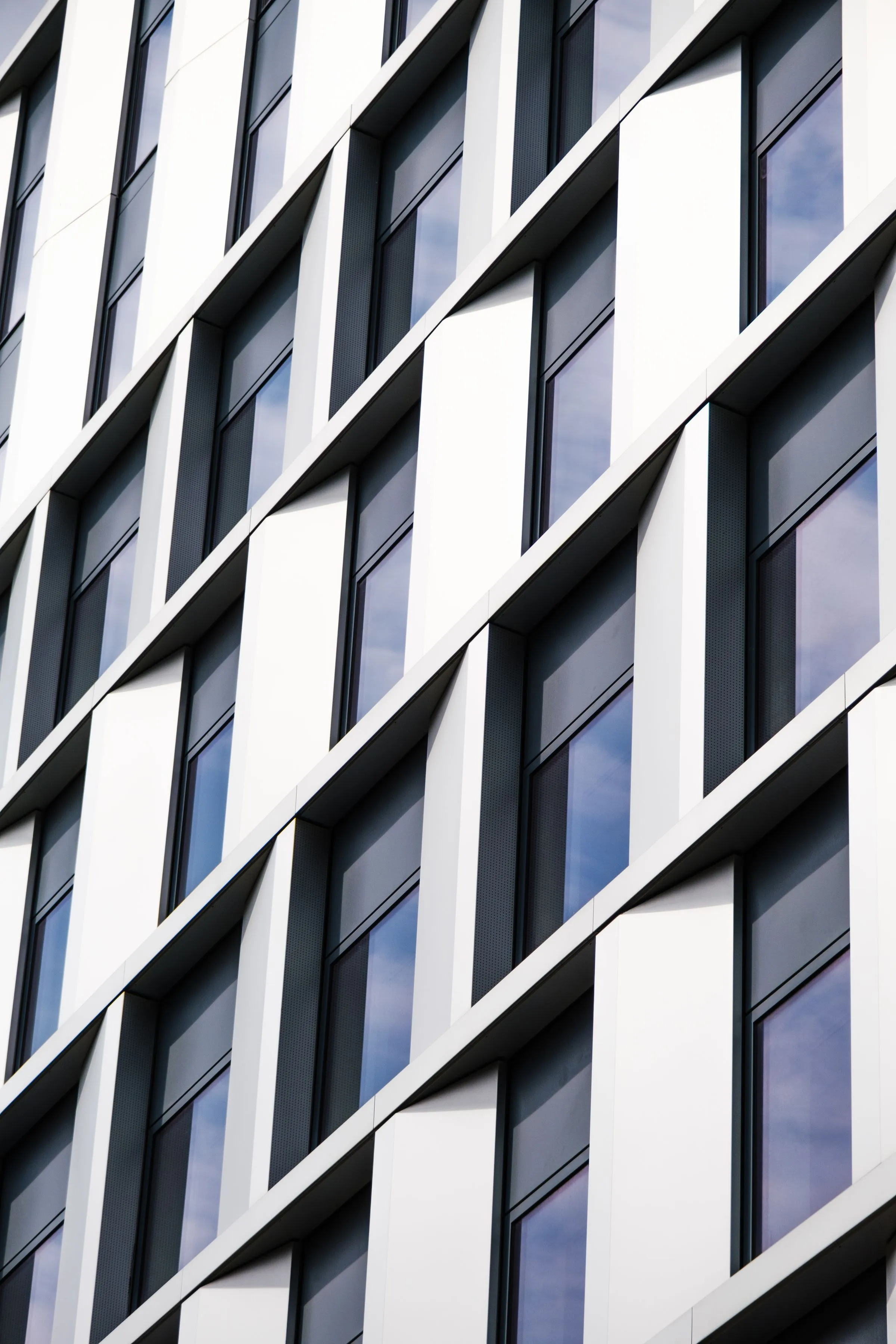 Fachada de un edificio de oficinas moderno con paneles blancos y ventanas.